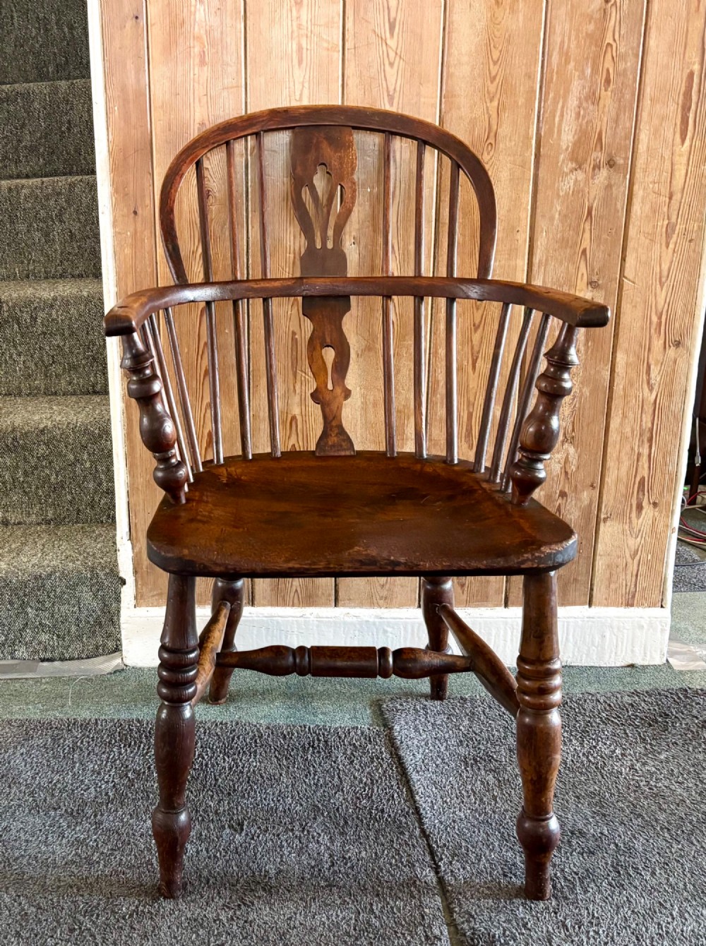A 19th-century dark elm Windsor armchair featuring a curved hoop back, central pierced splat, turned spindles, curved armrests, shaped seat, and turned legs joined by stretchers. View VI