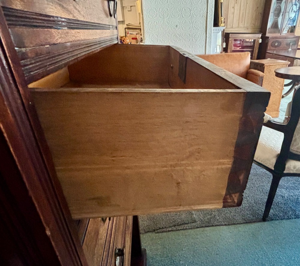 An early 20th-century tall and narrow mahogany chest featuring five drawers over an open lower section with vertical dividers. View VII