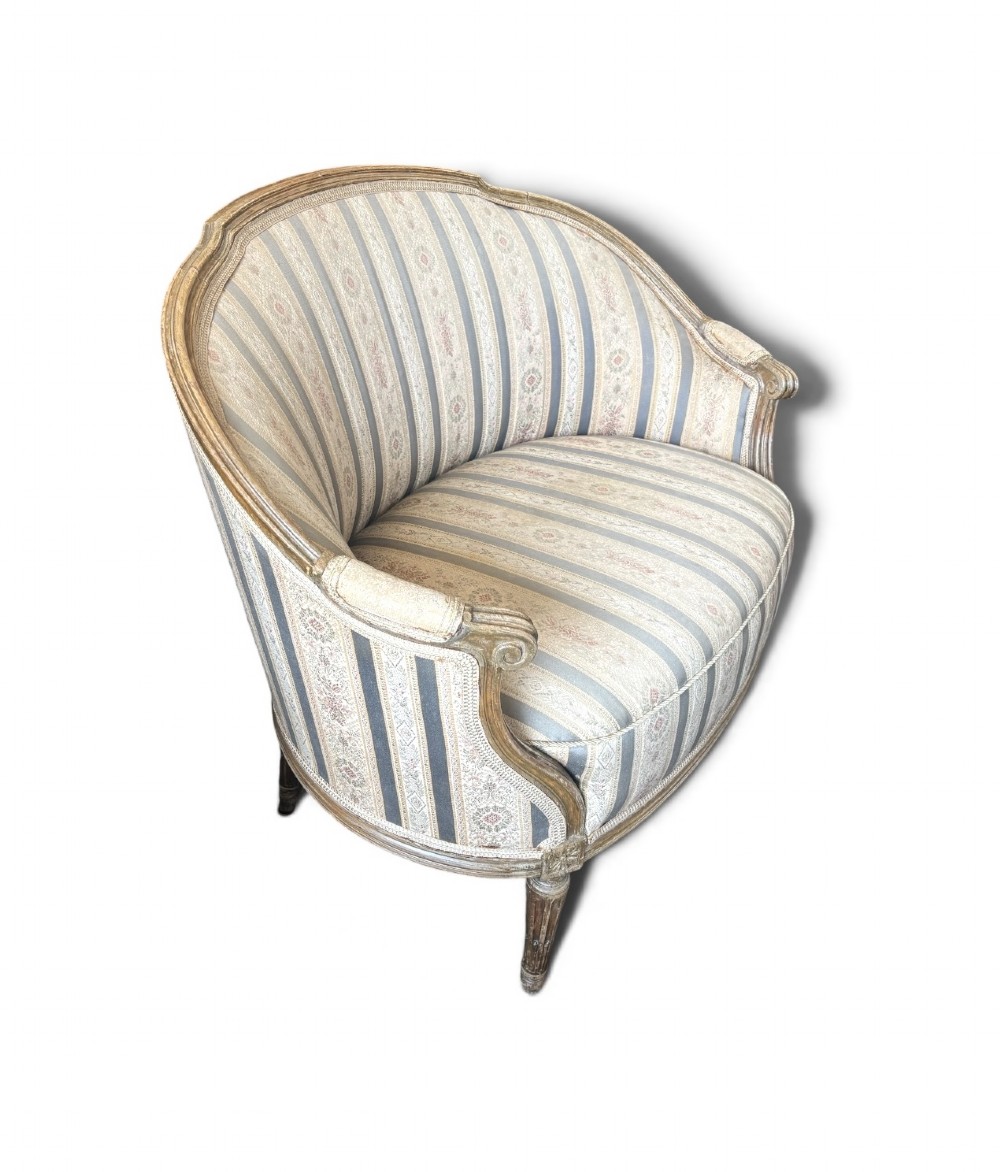 A Louis XVI style small settee featuring a curved barrel back, striped upholstery in grey and blue tones, and carved fluted legs.