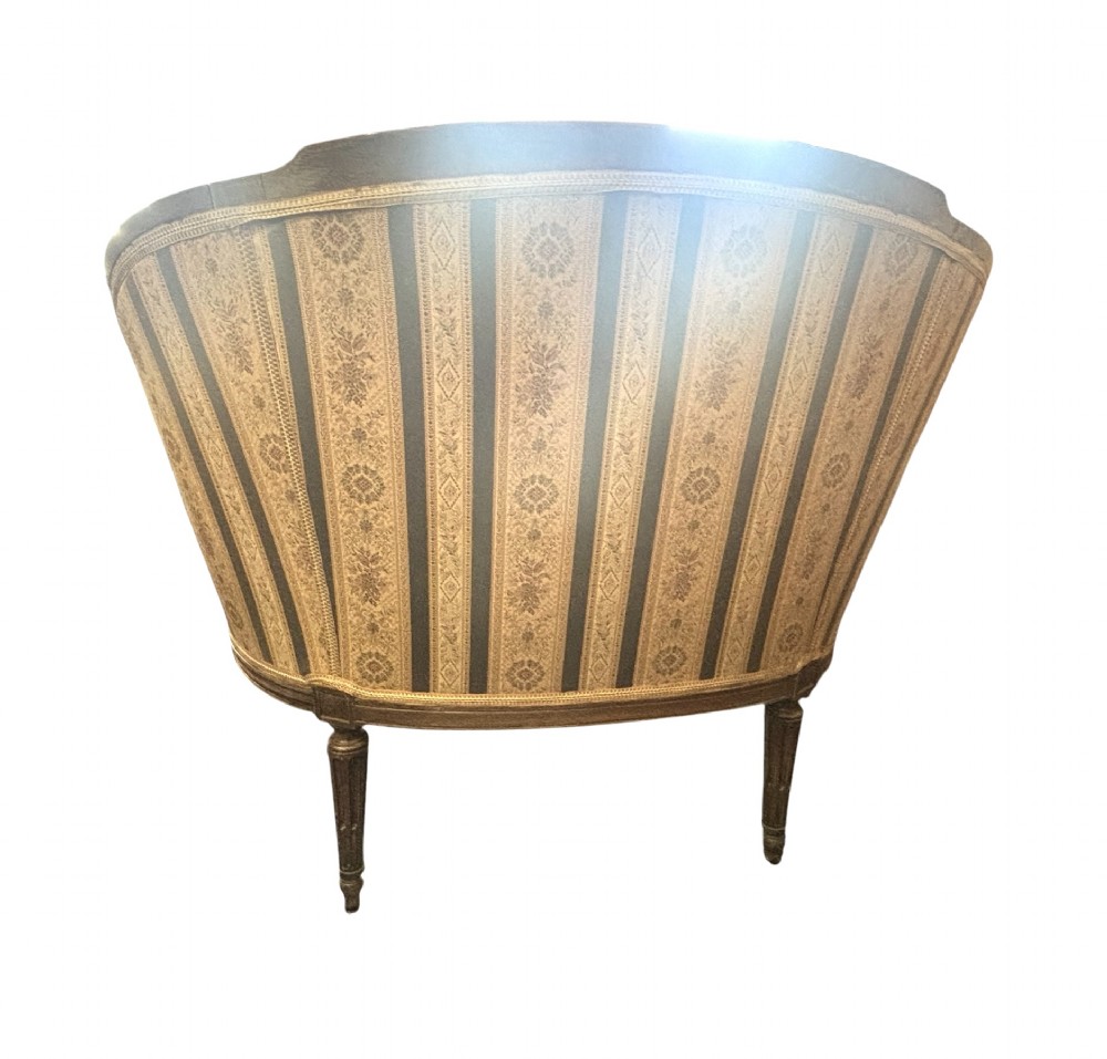 A Louis XVI style small settee featuring a curved barrel back, striped upholstery in grey and blue tones, and carved fluted legs. View IV