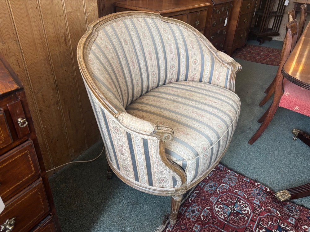 A Louis XVI style small settee featuring a curved barrel back, striped upholstery in grey and blue tones, and carved fluted legs. View V