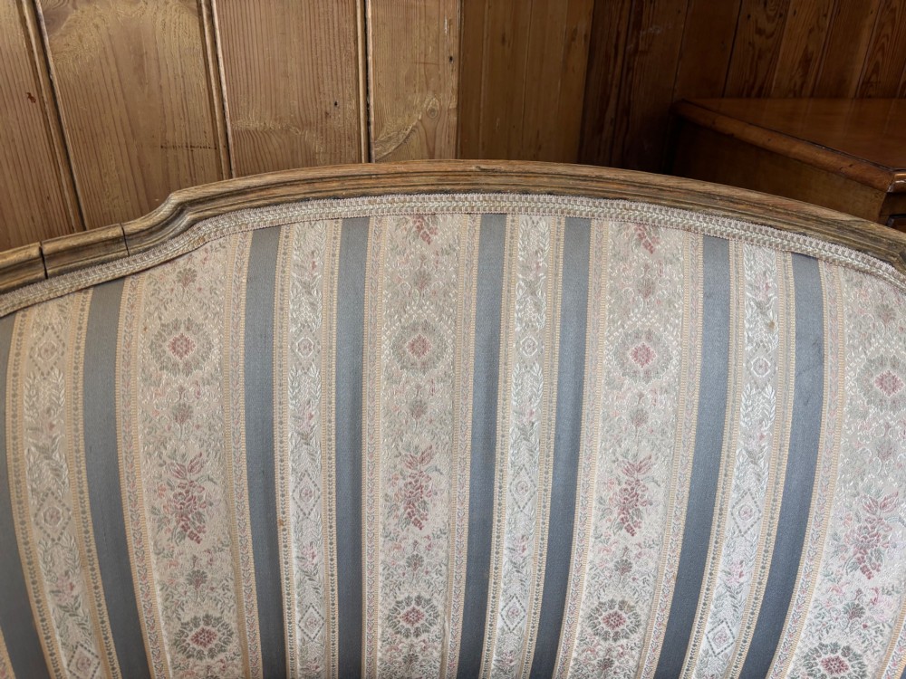 A Louis XVI style small settee featuring a curved barrel back, striped upholstery in grey and blue tones, and carved fluted legs. View VI