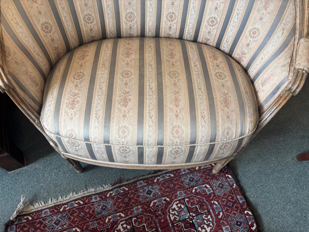 A Louis XVI style small settee featuring a curved barrel back, striped upholstery in grey and blue tones, and carved fluted legs. View VII