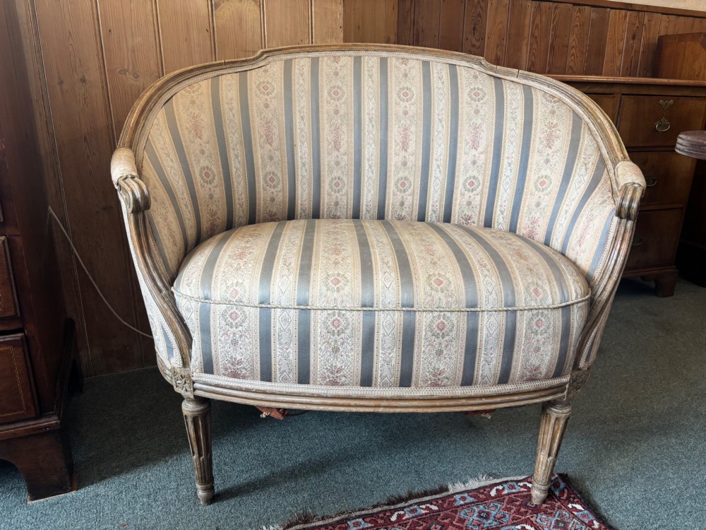 A Louis XVI style small settee featuring a curved barrel back, striped upholstery in grey and blue tones, and carved fluted legs. View VIII