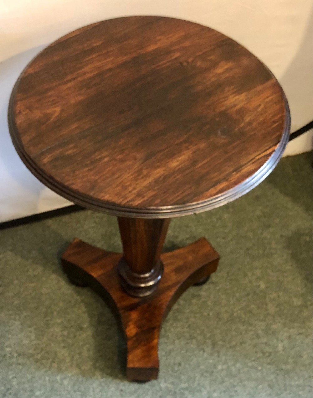 A Victorian rosewood wine table with a round top resting on a central column and a triform base.