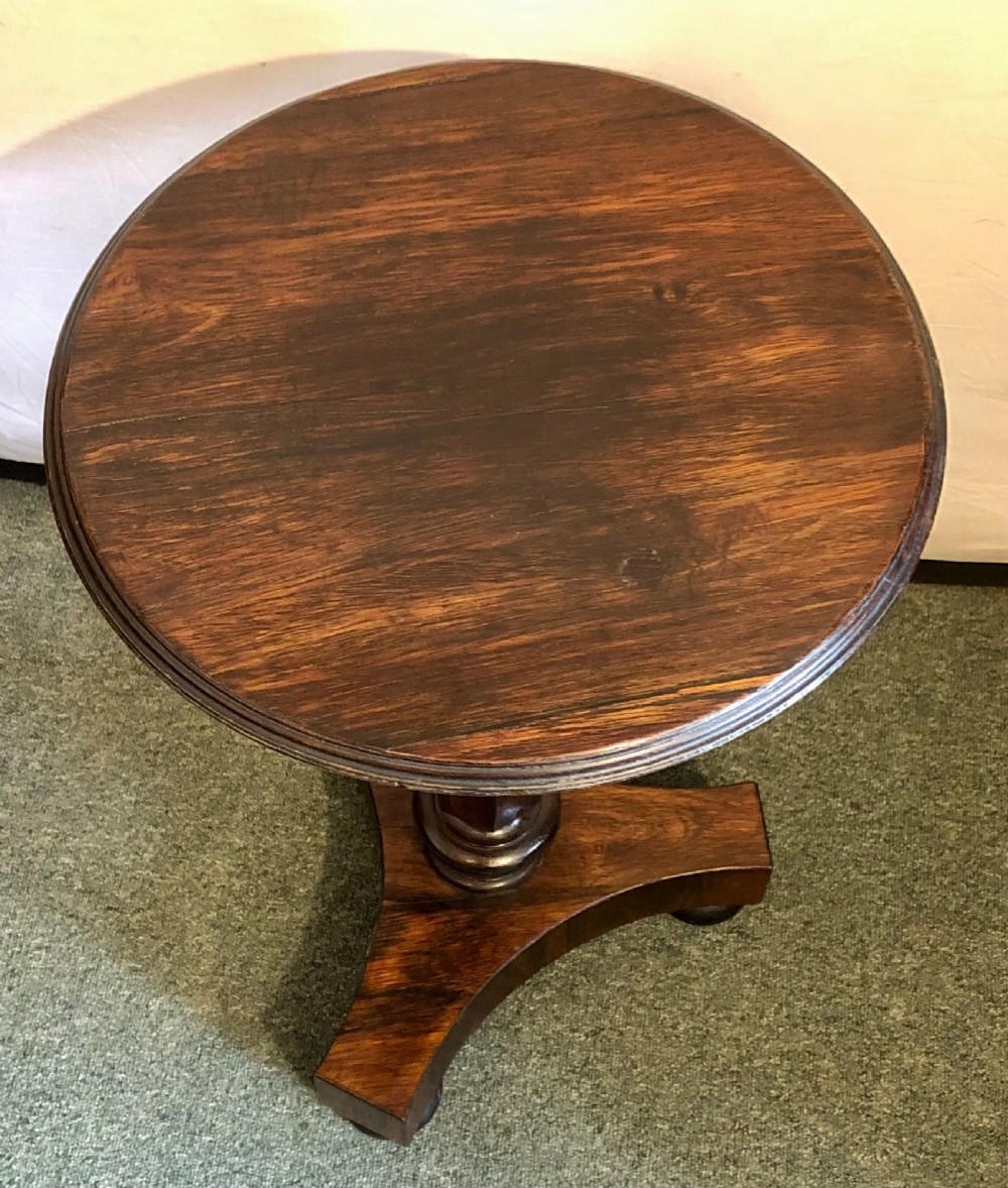 A Victorian rosewood wine table with a round top resting on a central column and a triform base. View II