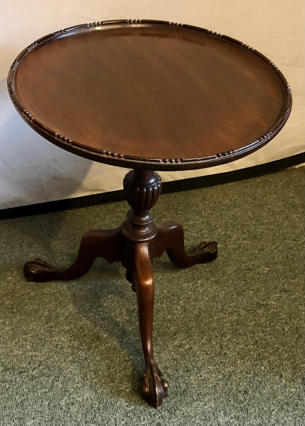 A small early twentieth-century mahogany tripod wine table featuring a circular top with a beaded rim, turned stem, and three cabriole legs.