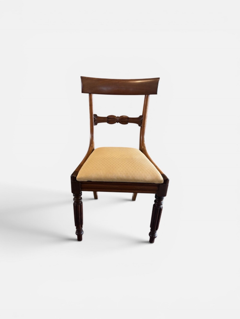 A set of eight 19th-century mahogany dining chairs with curved crest rails, carved central back bars, upholstered seats, and turned front legs. View II