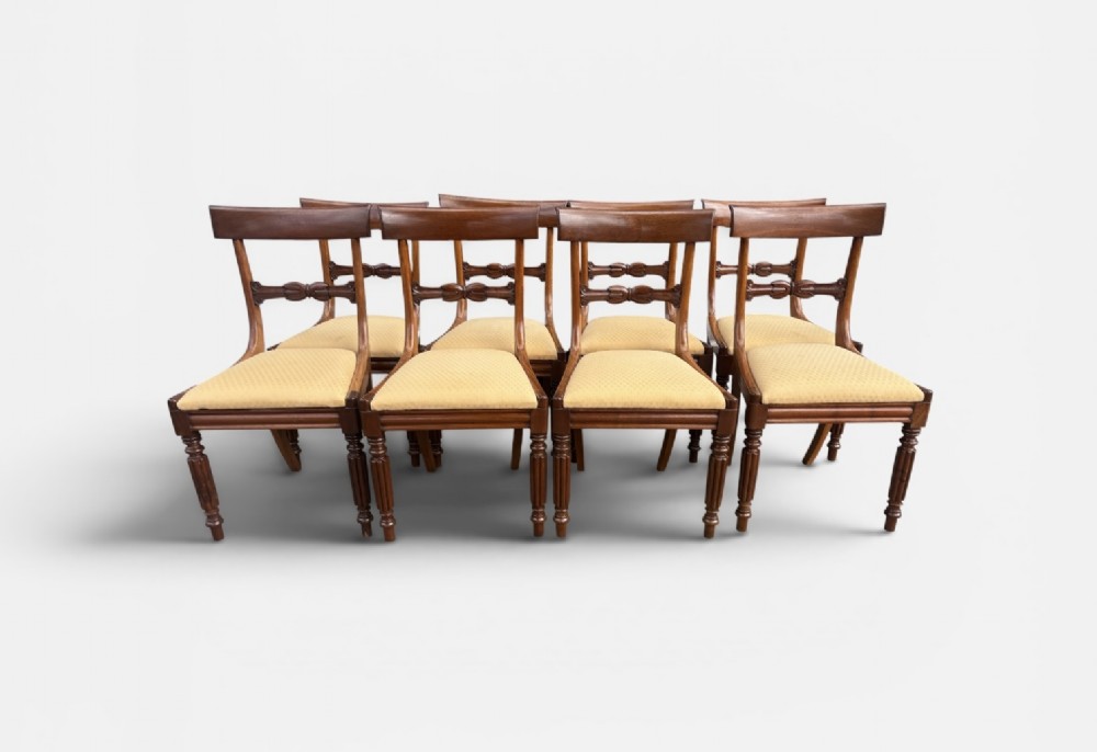 A set of eight 19th-century mahogany dining chairs with curved crest rails, carved central back bars, upholstered seats, and turned front legs. View III