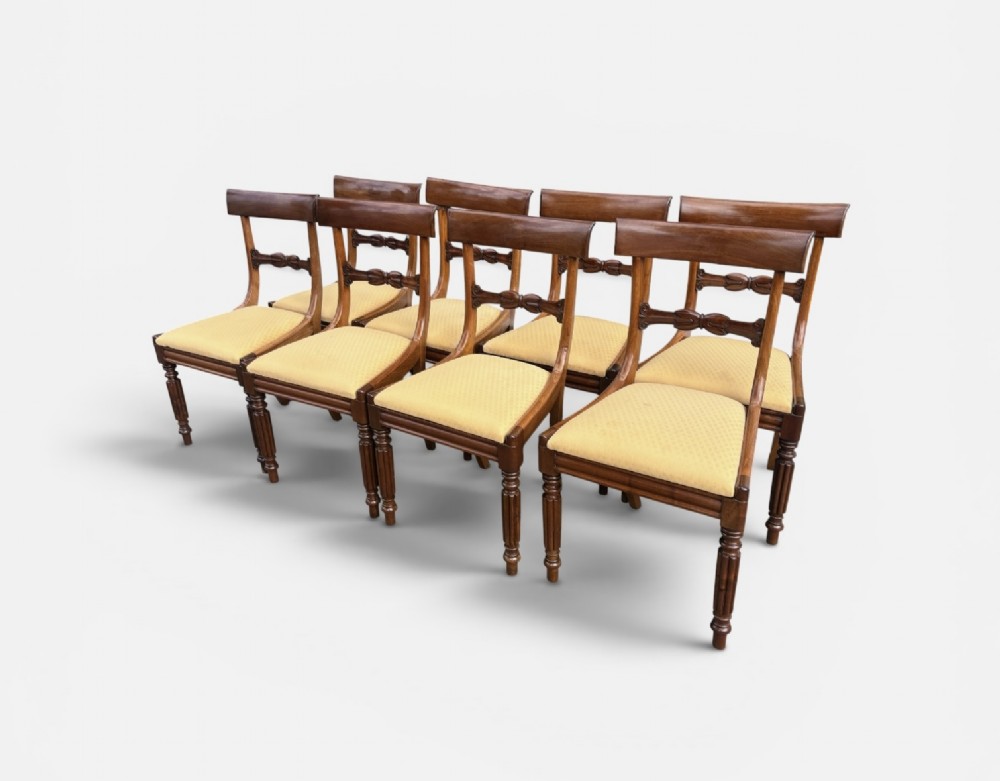 A set of eight 19th-century mahogany dining chairs with curved crest rails, carved central back bars, upholstered seats, and turned front legs. View IV