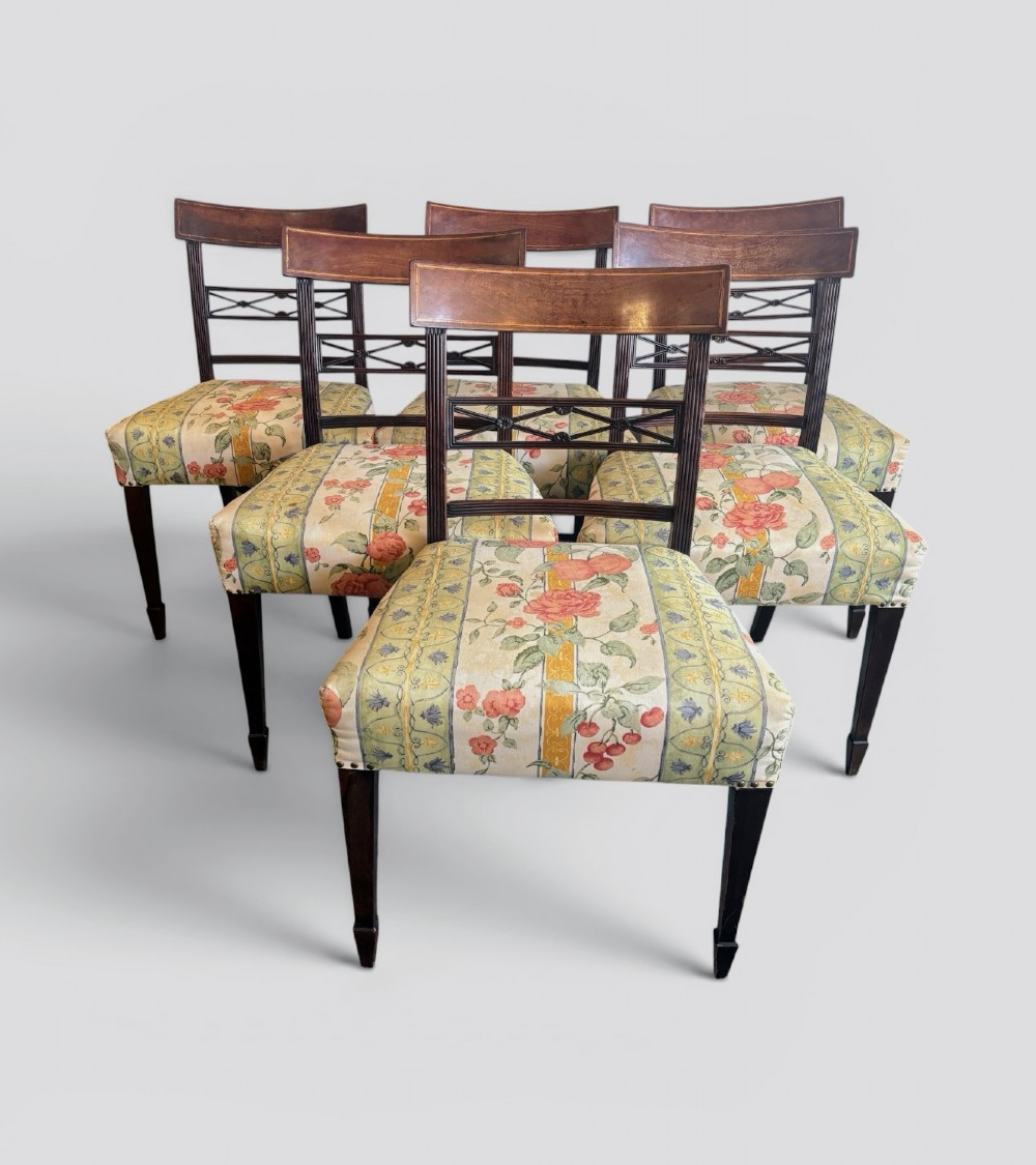 A set of six early nineteenth century mahogany dining chairs featuring tablet top rails, reeded frames, lattice splats, and floral striped fabric seats.