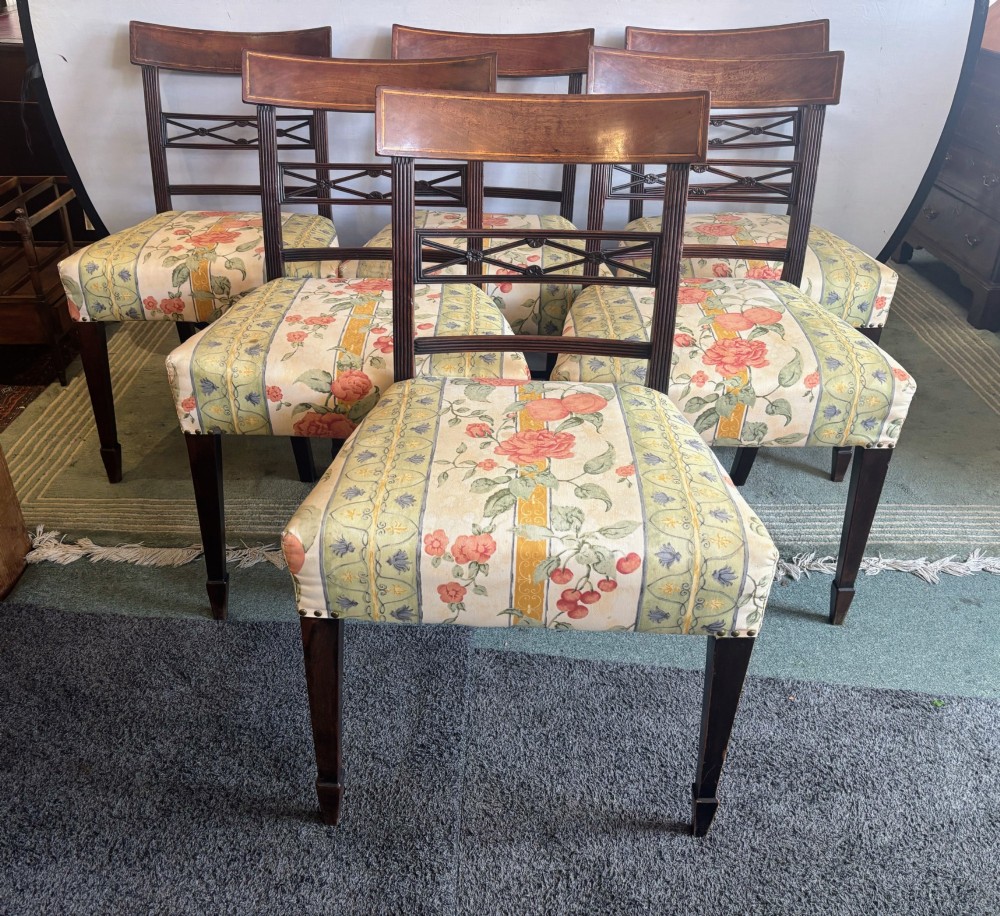 A set of six early nineteenth century mahogany dining chairs featuring tablet top rails, reeded frames, lattice splats, and floral striped fabric seats. View X