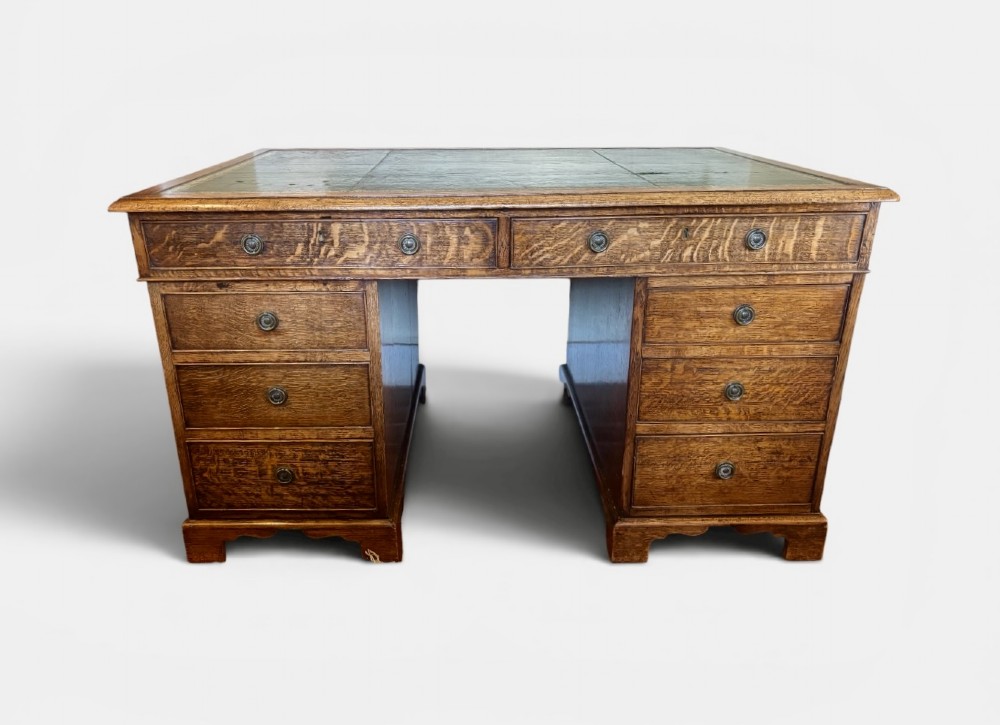 A large Victorian oak pedestal desk featuring a three-panel green leather inset writing top and nine drawers with turned handles. View II