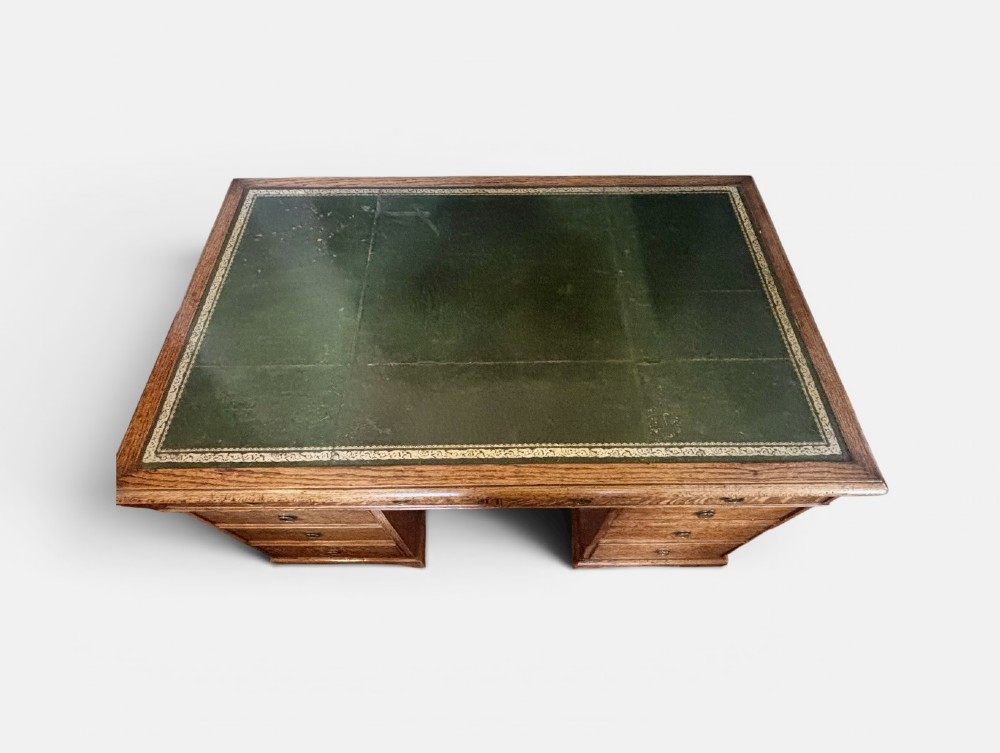 A large Victorian oak pedestal desk featuring a three-panel green leather inset writing top and nine drawers with turned handles. View III
