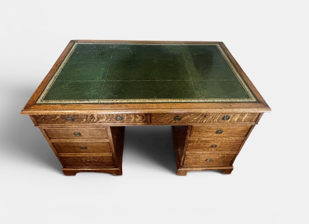 A large Victorian oak pedestal desk featuring a three-panel green leather inset writing top and nine drawers with turned handles. View IV