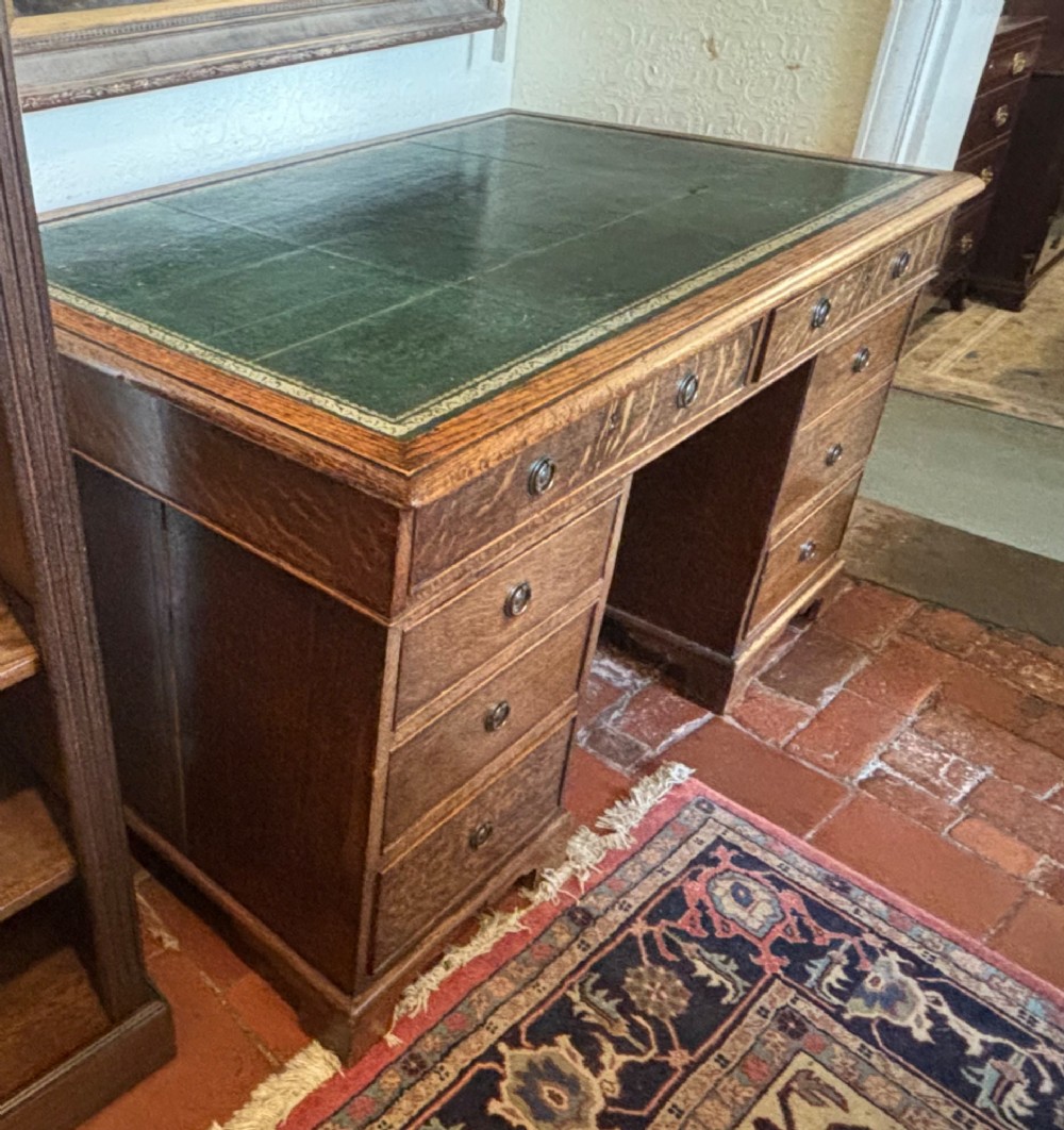 A large Victorian oak pedestal desk featuring a three-panel green leather inset writing top and nine drawers with turned handles. View VI