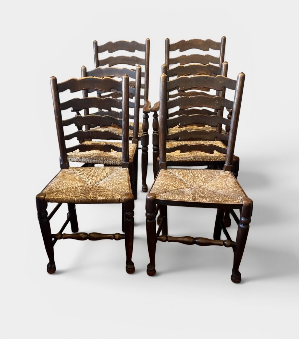 A set of dark oak ladder back chairs featuring woven rush seats and turned front legs.