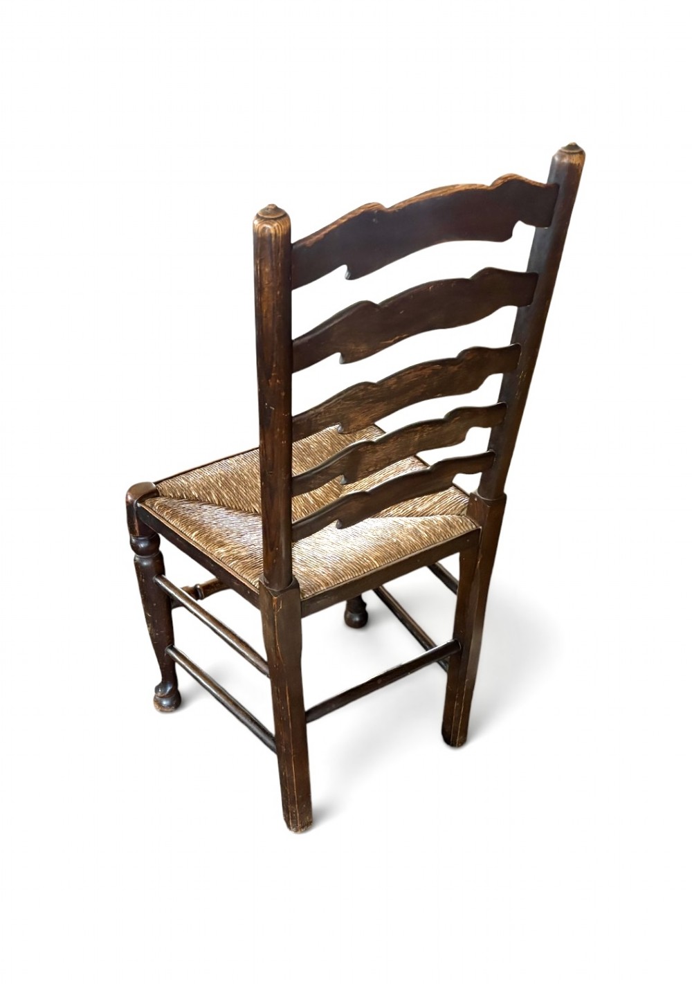 A set of dark oak ladder back chairs featuring woven rush seats and turned front legs. View VII
