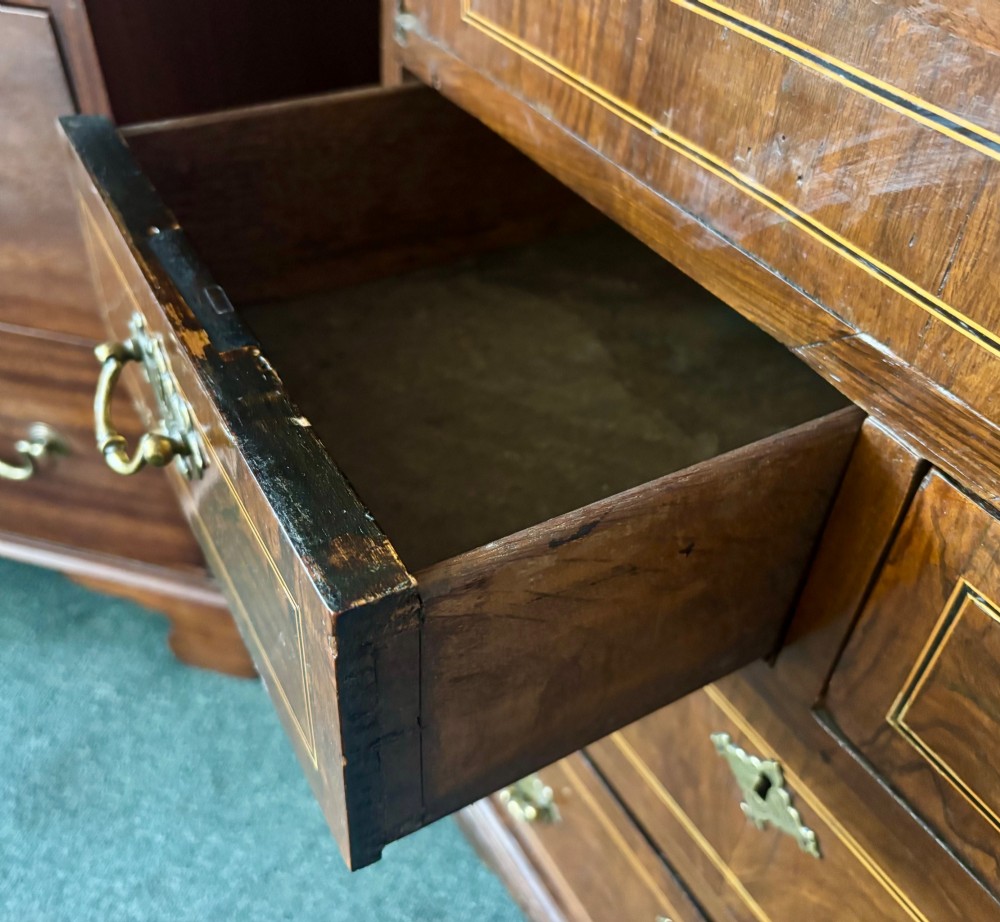An antique George III walnut slant-front bureau desk featuring brass drop handles, feather-banded inlay, and a graduated drawer base on bracket feet. View VI