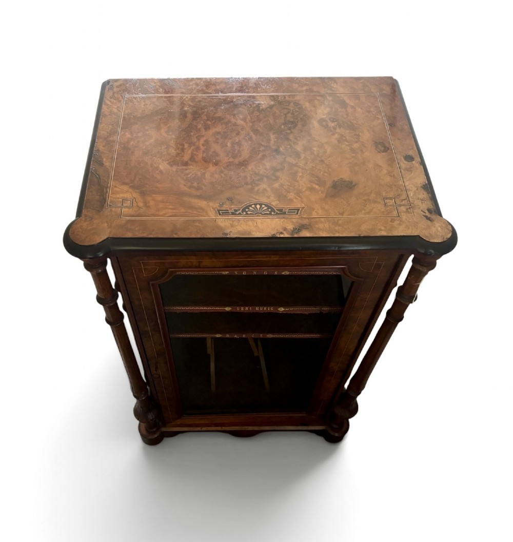 A nineteenth-century Victorian burr walnut music cabinet featuring a single glazed door, turned side pilasters, and internal shelving with embossed leather trim. View II