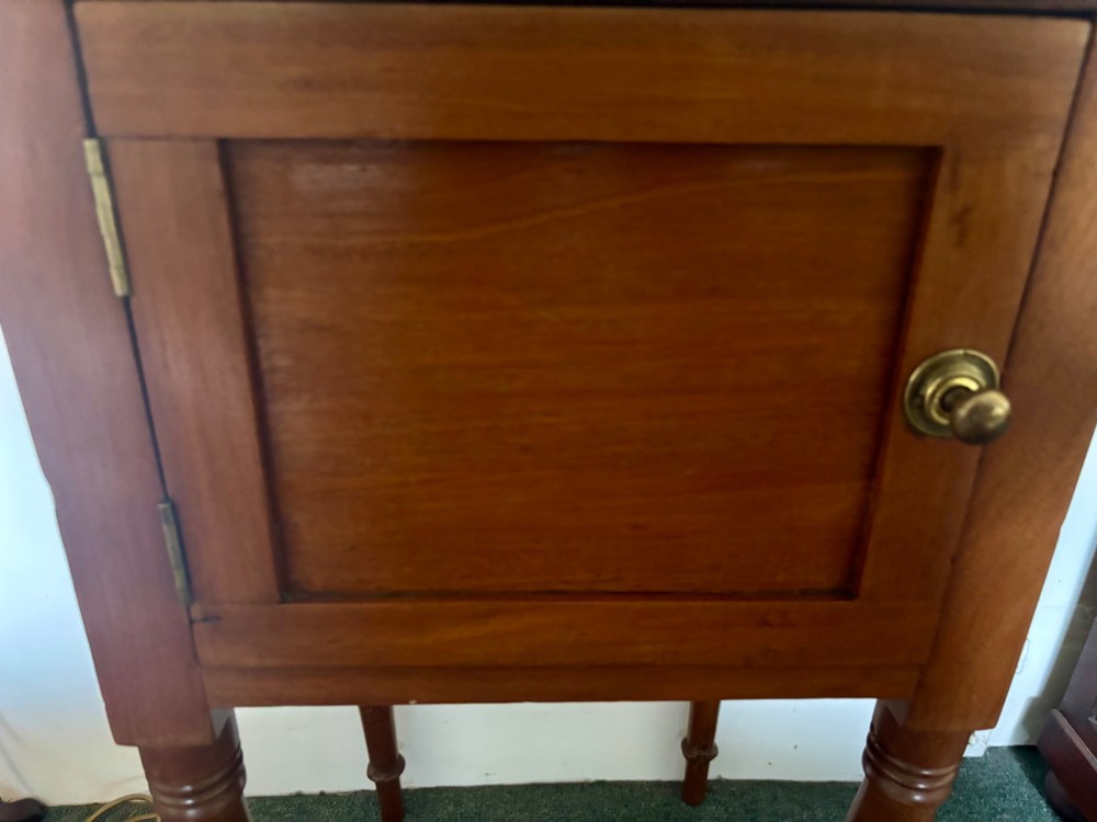 A 19th-century mahogany bedside cupboard featuring a single panelled cupboard door with a brass knob and tall turned legs. View V