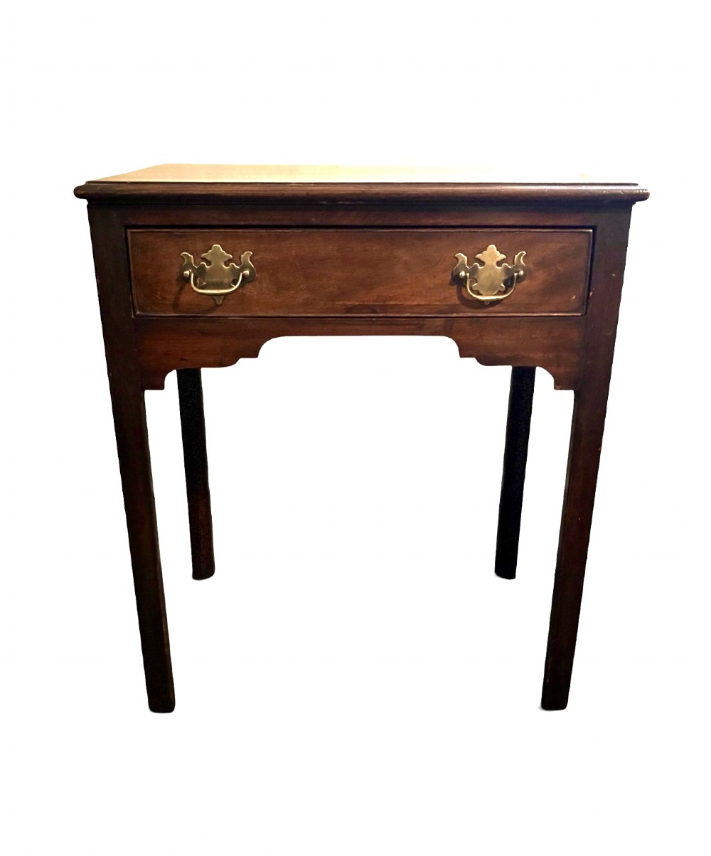 A George III dark mahogany lowboy side table with a rectangular top, a single wide drawer fitted with brass handles, a shaped apron, and four straight legs. View II