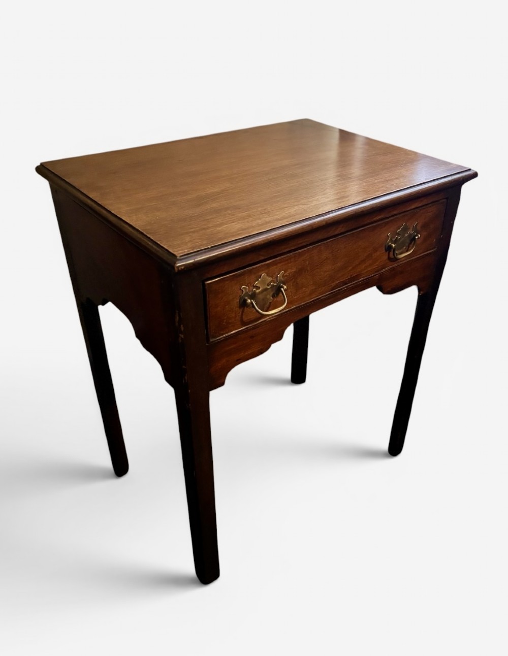 A George III dark mahogany lowboy side table with a rectangular top, a single wide drawer fitted with brass handles, a shaped apron, and four straight legs. View IV