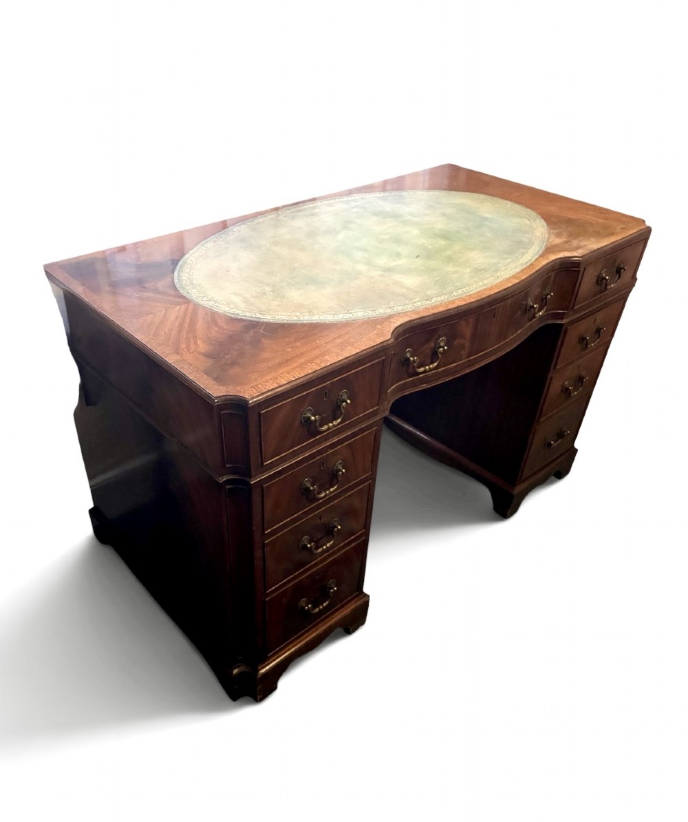 A mahogany pedestal desk featuring an inset green leather top with gilded tooling, brass drop handles, and bracket feet. View II