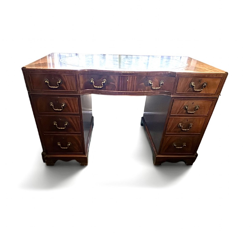 A mahogany pedestal desk featuring an inset green leather top with gilded tooling, brass drop handles, and bracket feet. View III