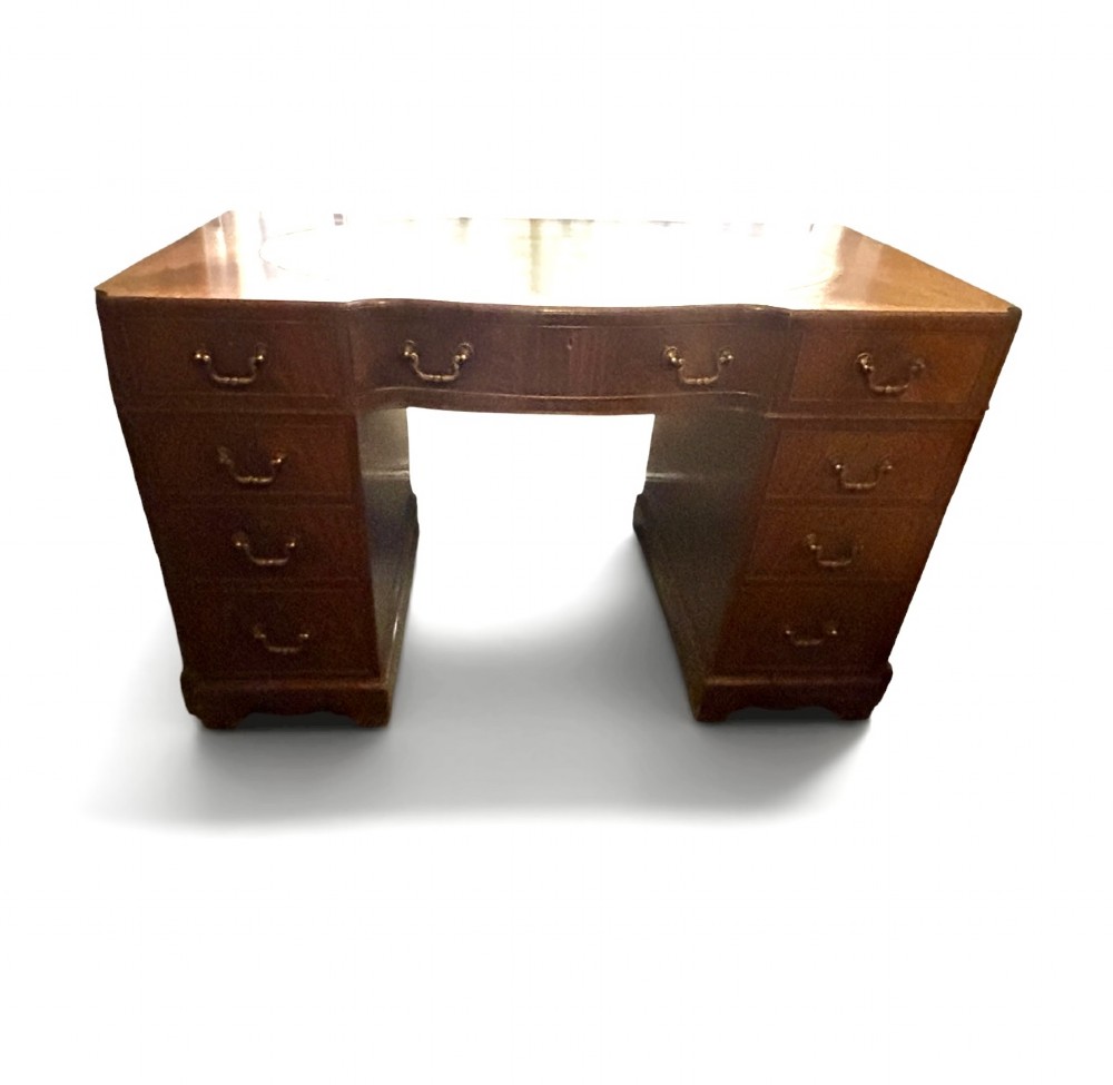 A mahogany pedestal desk featuring an inset green leather top with gilded tooling, brass drop handles, and bracket feet. View IV