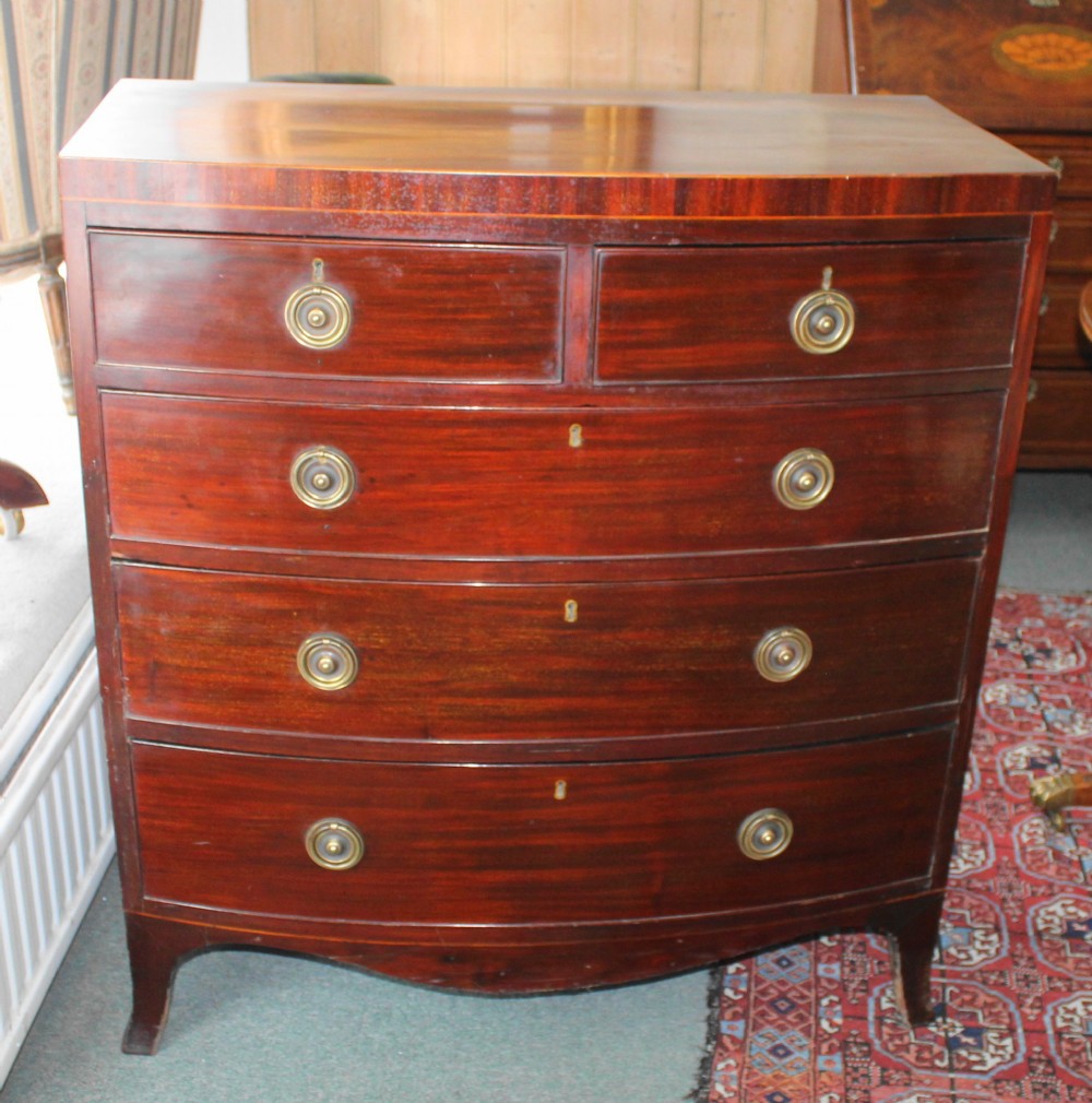 A Regency mahogany bow-front chest of drawers featuring two short drawers over three long graduated drawers with circular brass drop ring handles and splayed bracket feet.