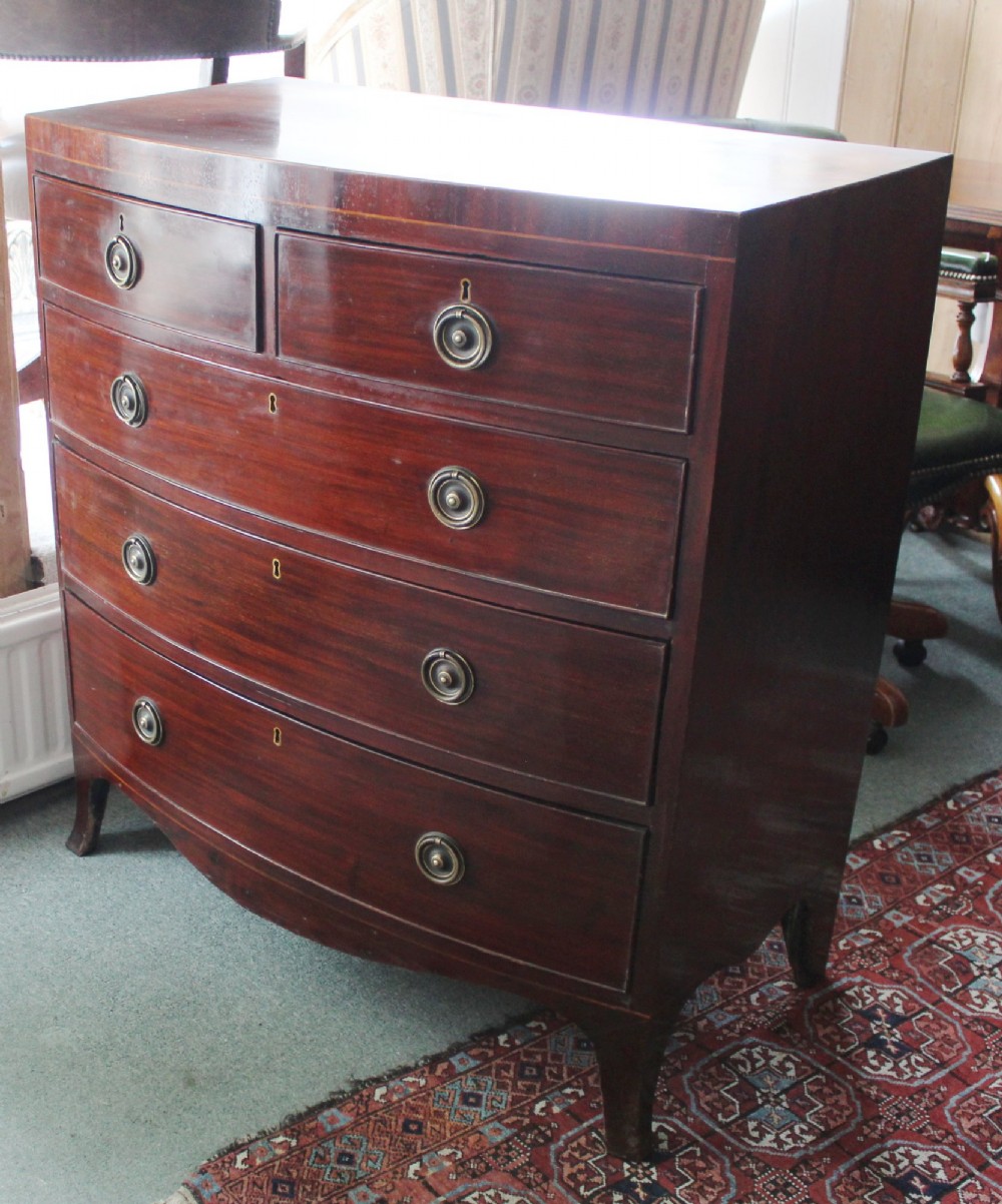 A Regency mahogany bow-front chest of drawers featuring two short drawers over three long graduated drawers with circular brass drop ring handles and splayed bracket feet. View II