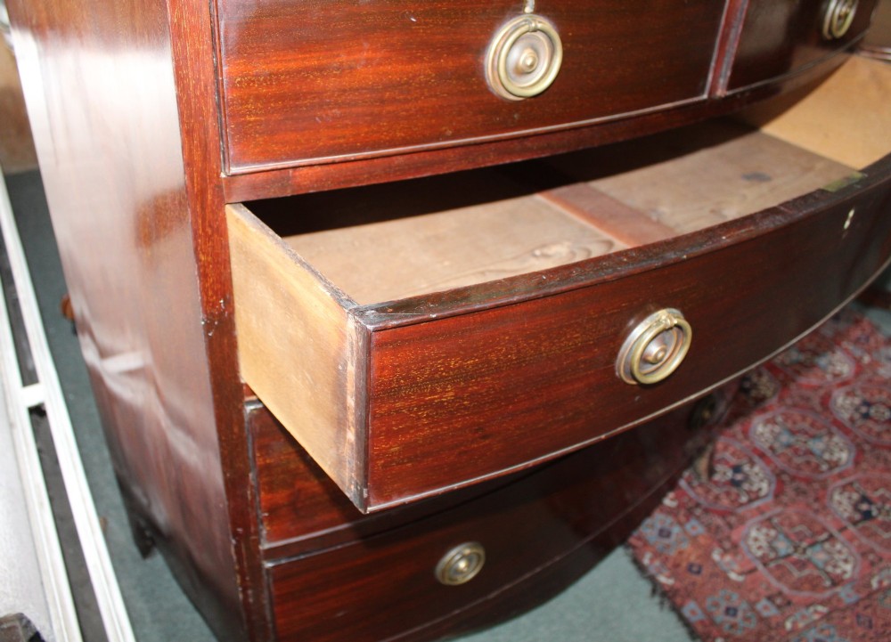 A Regency mahogany bow-front chest of drawers featuring two short drawers over three long graduated drawers with circular brass drop ring handles and splayed bracket feet. View III