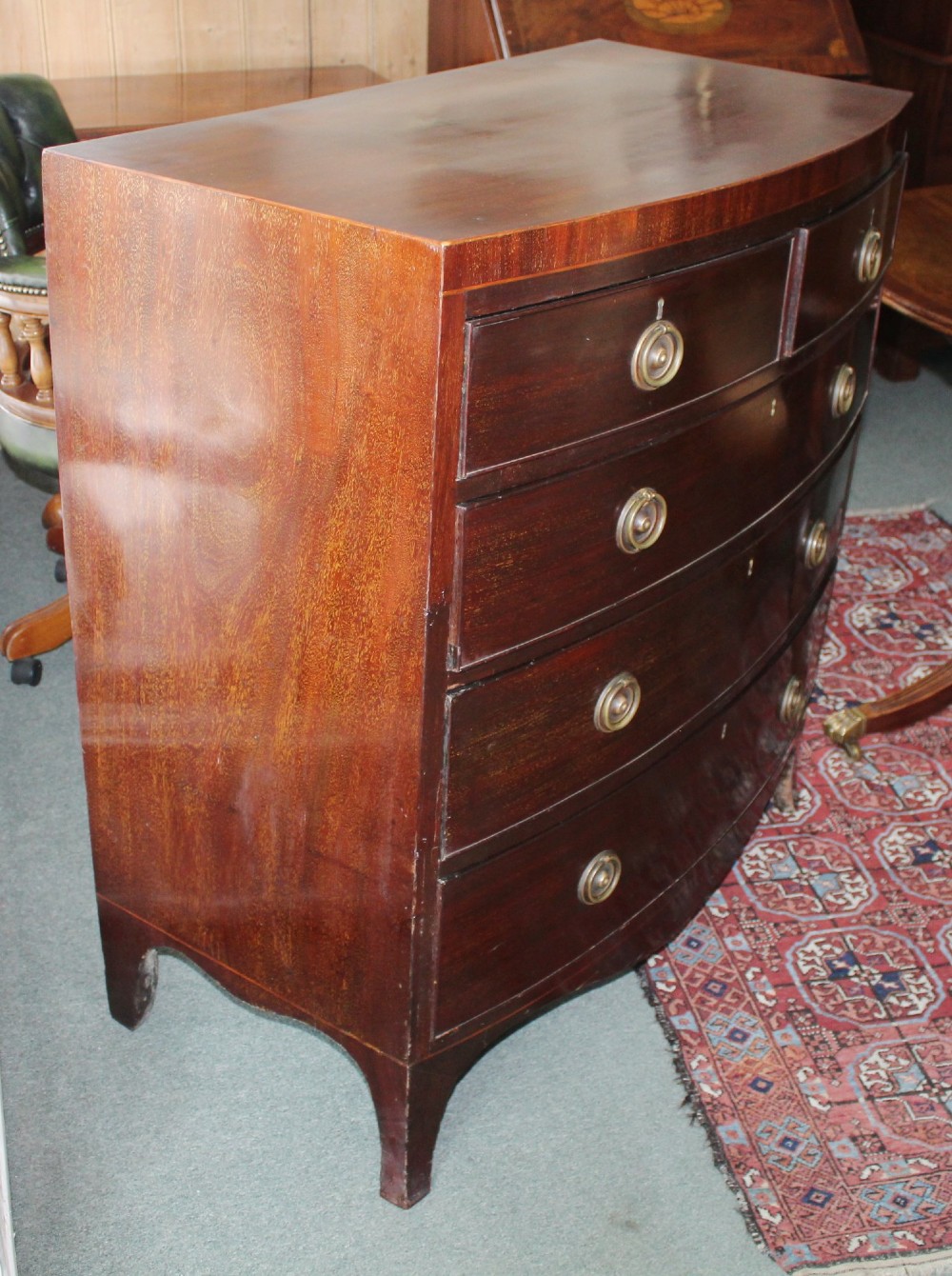 A Regency mahogany bow-front chest of drawers featuring two short drawers over three long graduated drawers with circular brass drop ring handles and splayed bracket feet. View IV