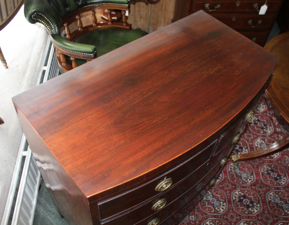 A Regency mahogany bow-front chest of drawers featuring two short drawers over three long graduated drawers with circular brass drop ring handles and splayed bracket feet. View VII