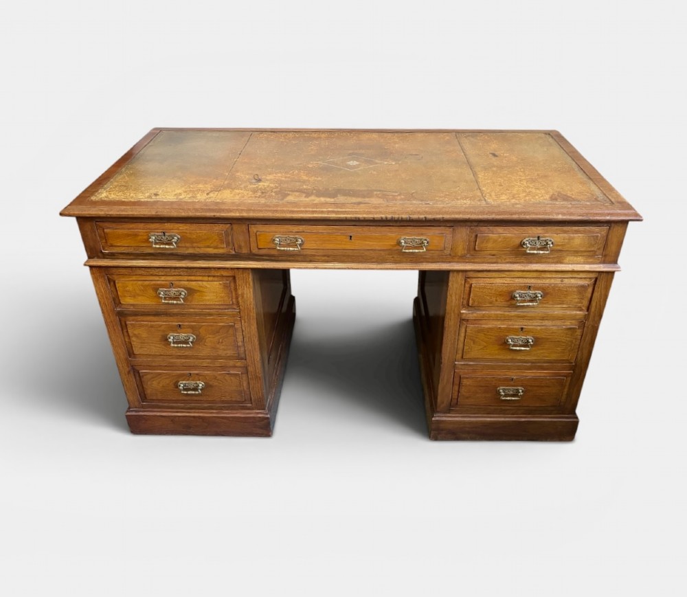 A Victorian walnut pedestal desk featuring nine drawers, brass handles, and a leather insert top surface. View II