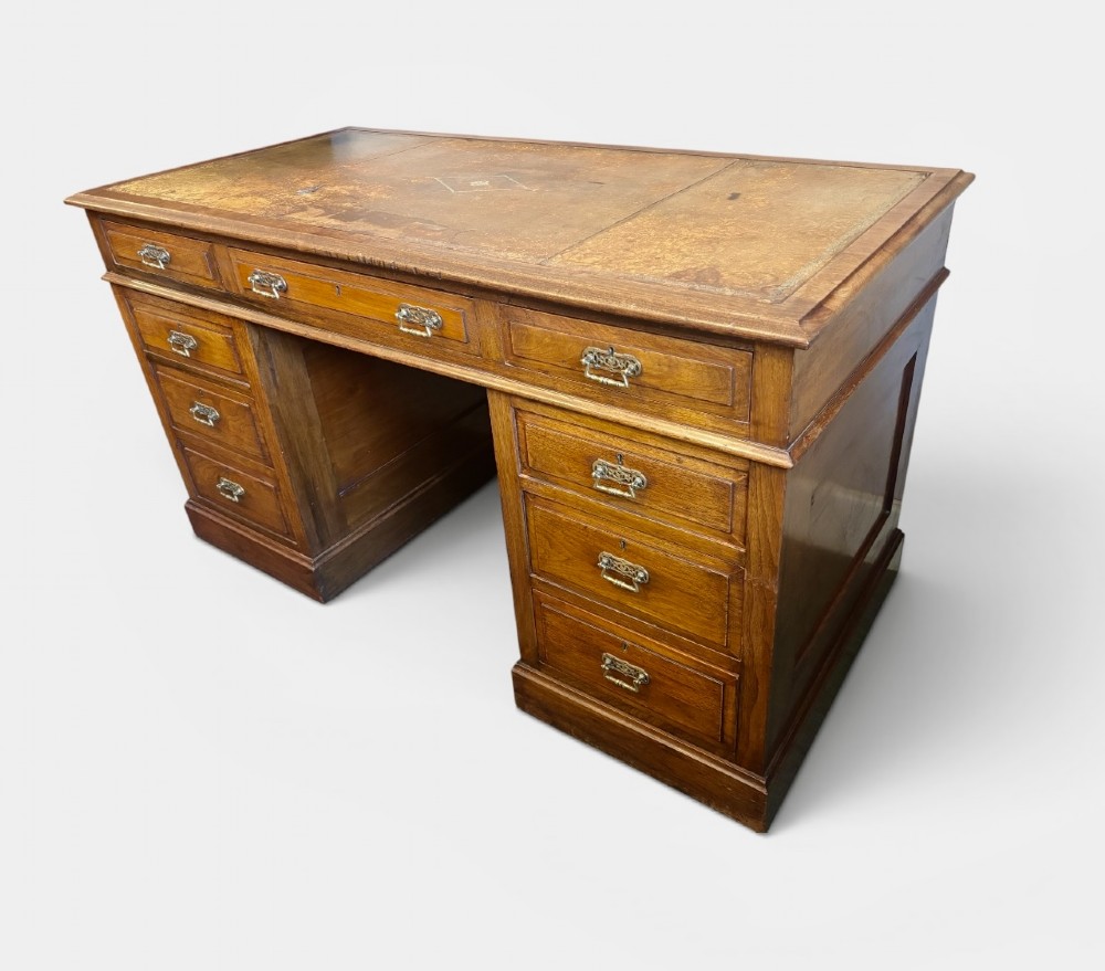 A Victorian walnut pedestal desk featuring nine drawers, brass handles, and a leather insert top surface. View III