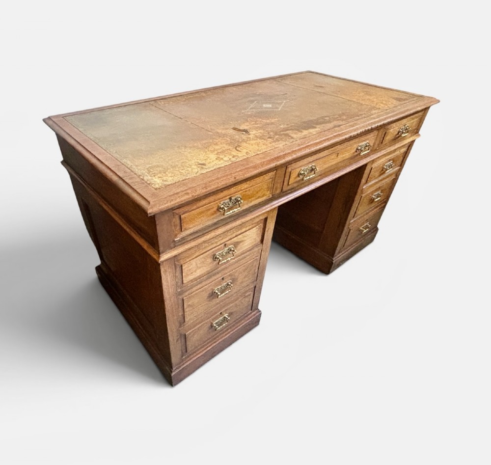 A Victorian walnut pedestal desk featuring nine drawers, brass handles, and a leather insert top surface. View IV