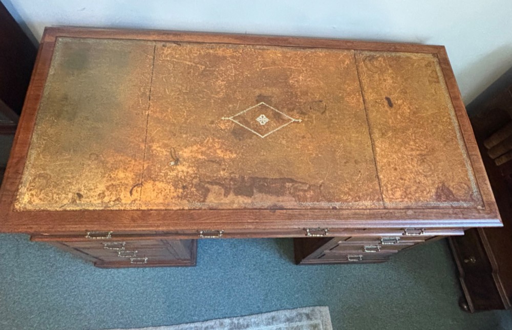 A Victorian walnut pedestal desk featuring nine drawers, brass handles, and a leather insert top surface. View VII