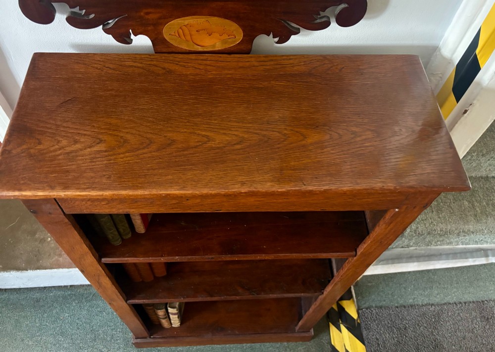 A narrow Edwardian oak open bookcase featuring adjustable wooden shelves and a simple plinth base. View V