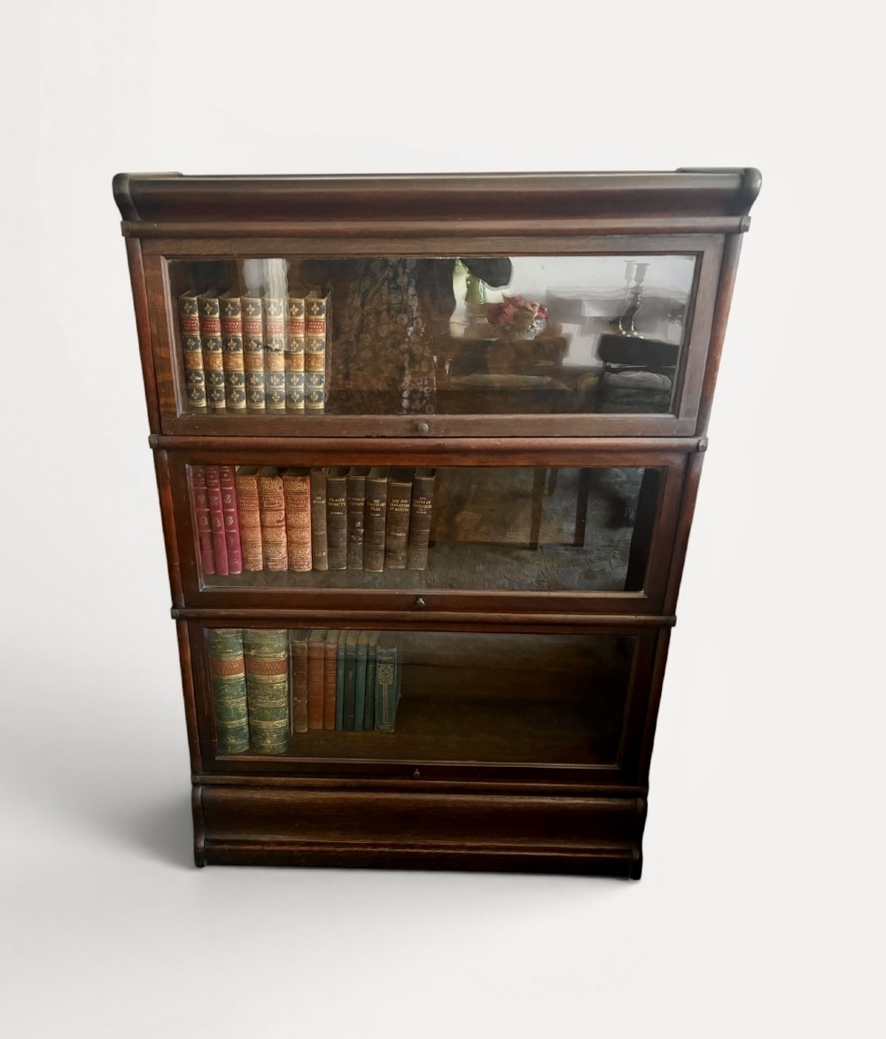 A three-tier Victorian dark oak barrister bookcase featuring glazed lifting doors with small brass knobs. View II