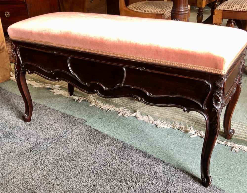 An Edwardian carved rosewood duet stool with a long, dusty-pink velvet upholstered top supported by cabriole legs. View III