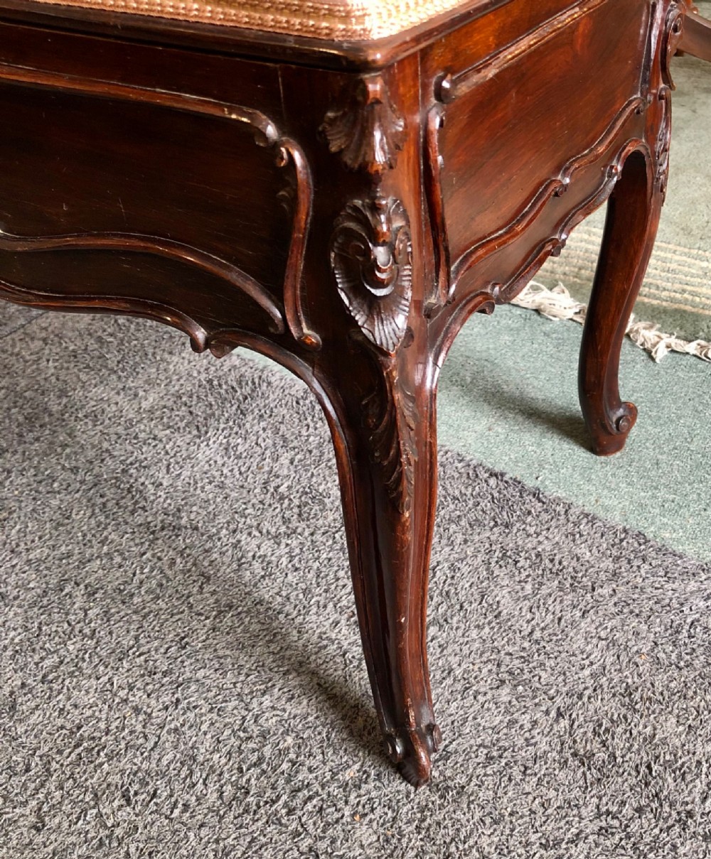 An Edwardian carved rosewood duet stool with a long, dusty-pink velvet upholstered top supported by cabriole legs. View VIII