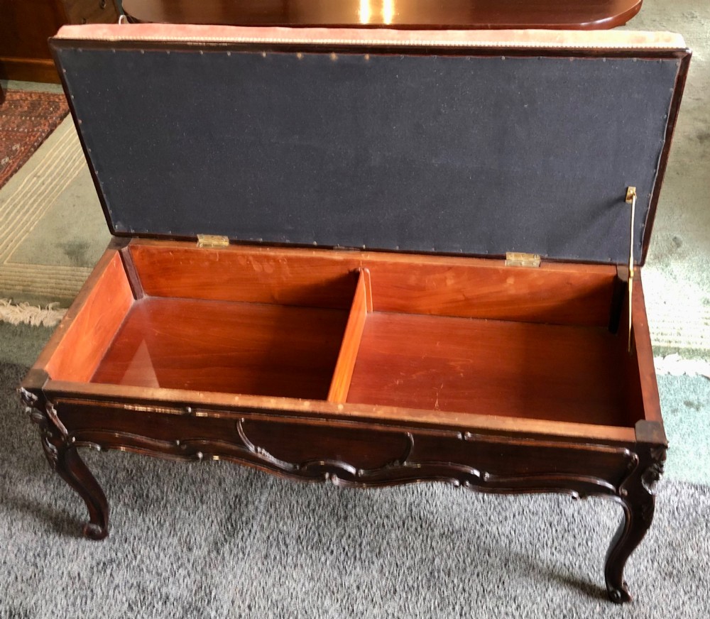 An Edwardian carved rosewood duet stool with a long, dusty-pink velvet upholstered top supported by cabriole legs. View X