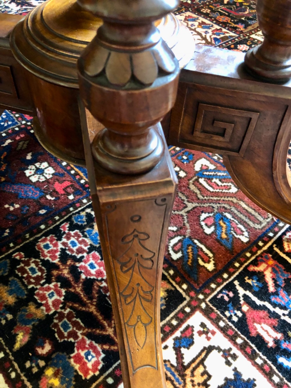 A Victorian oval burr walnut tilt-top table shown angled upright to display the wood veneer pattern and four splayed pedestal legs. View X