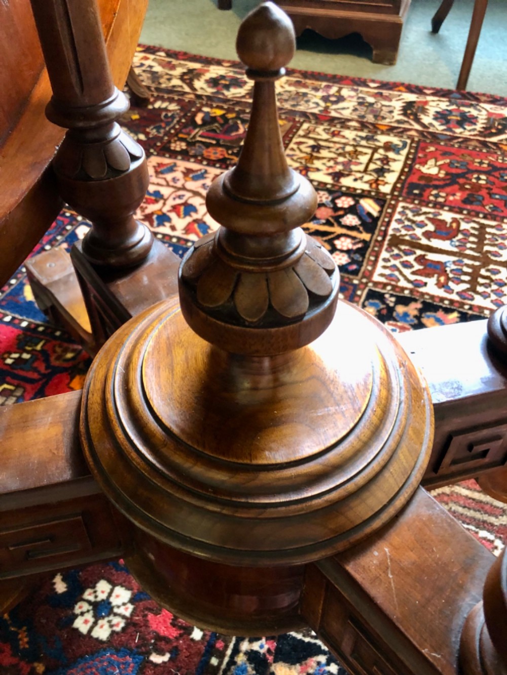 A Victorian oval burr walnut tilt-top table shown angled upright to display the wood veneer pattern and four splayed pedestal legs. View XI