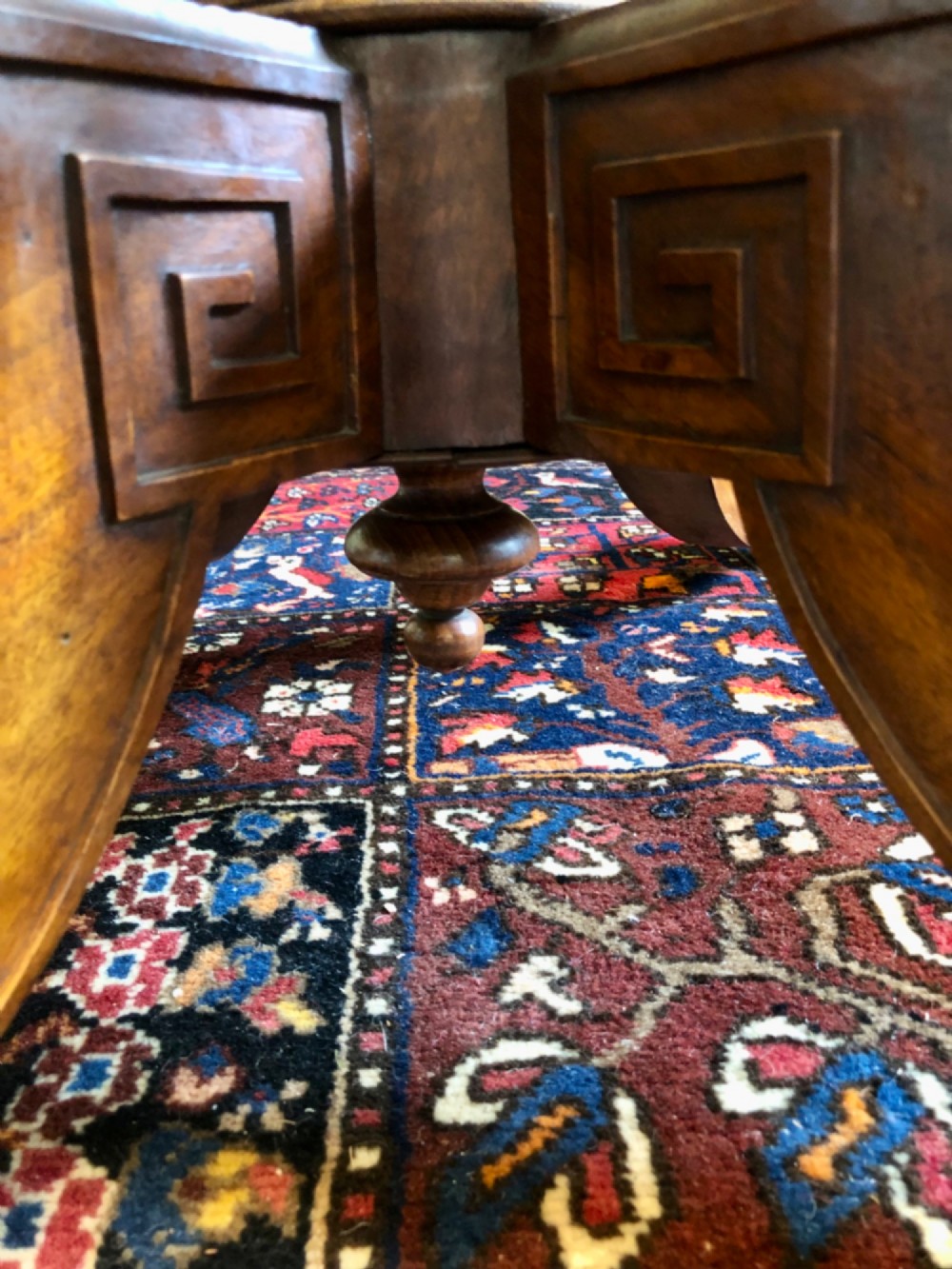 A Victorian oval burr walnut tilt-top table shown angled upright to display the wood veneer pattern and four splayed pedestal legs. View XII