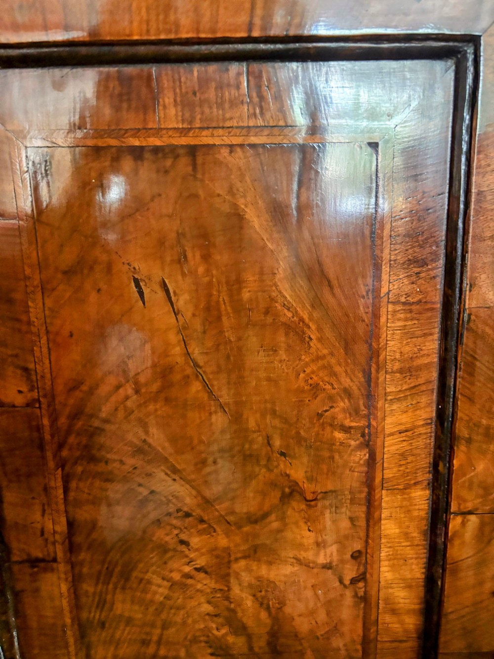 A George III walnut corner cupboard featuring a single panelled door with figured wood grain, brass H-hinges, and moulded cornice details. View III