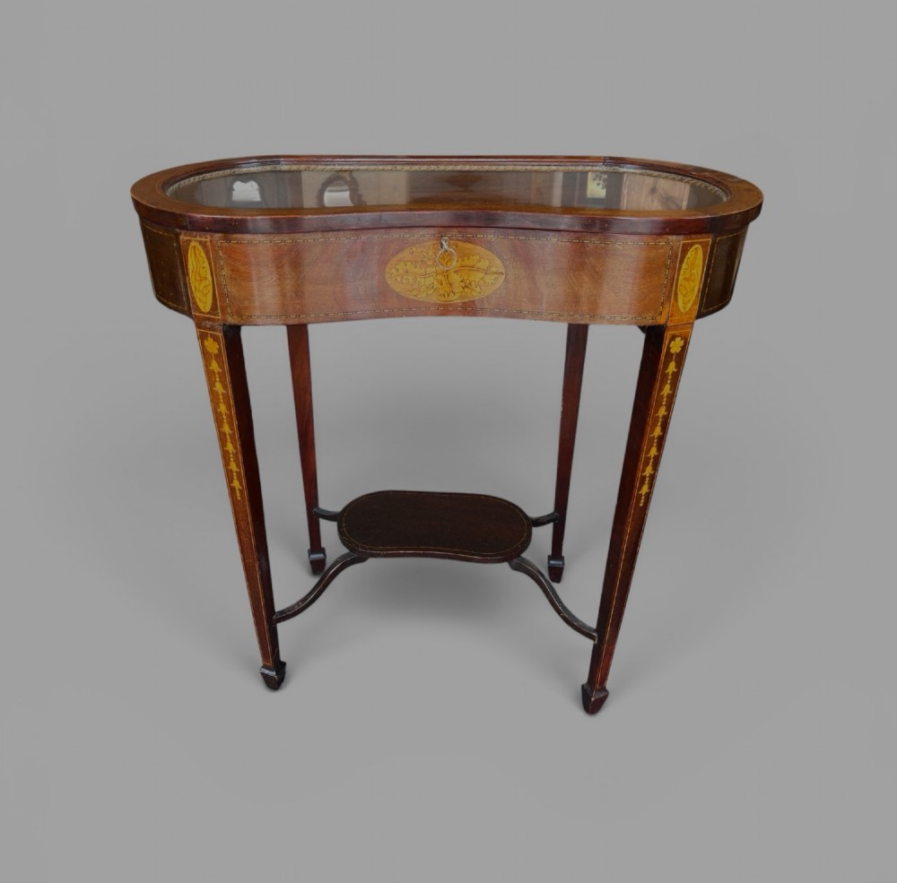 A kidney-shaped Edwardian mahogany display table with satinwood floral inlays, slender tapered legs, a glass top, and an undershelf. View III