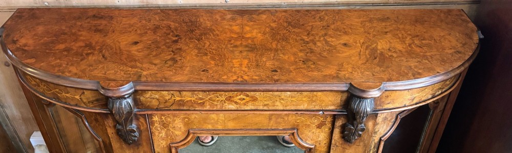 A Victorian walnut side cabinet featuring floral marquetry inlays, three glazed doors, carved corbels, and a shaped serpentine front. View III